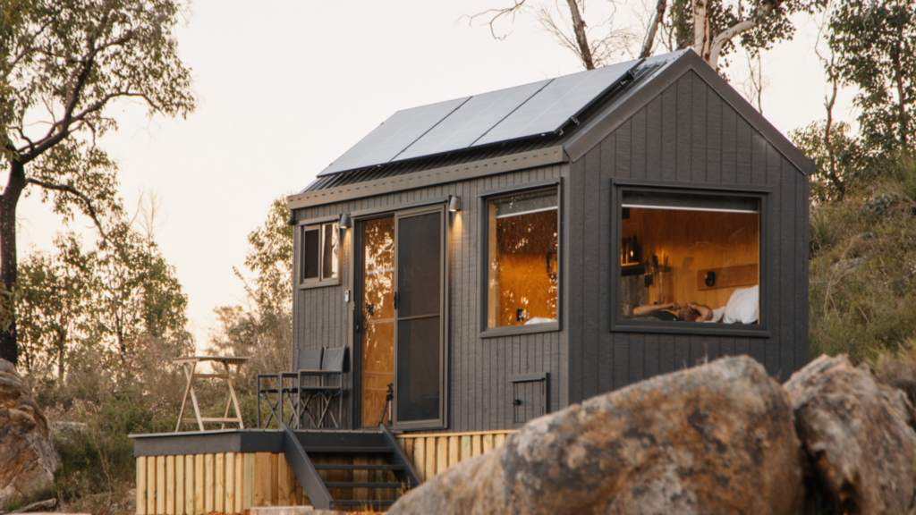 Exterior of Unyoked black wood tiny home with solar panels on A-frame roof