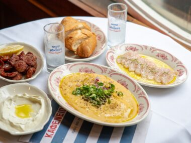 Five plates of food on a round table at Kafeneion.